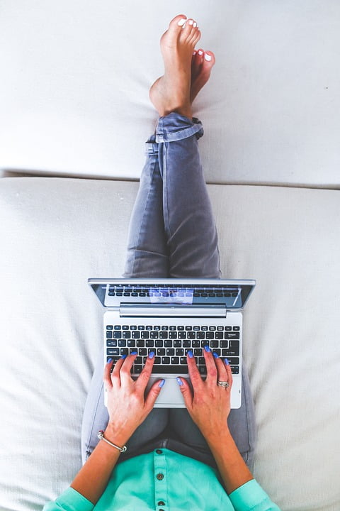 Frau auf Sofa mit Laptop im Schoß